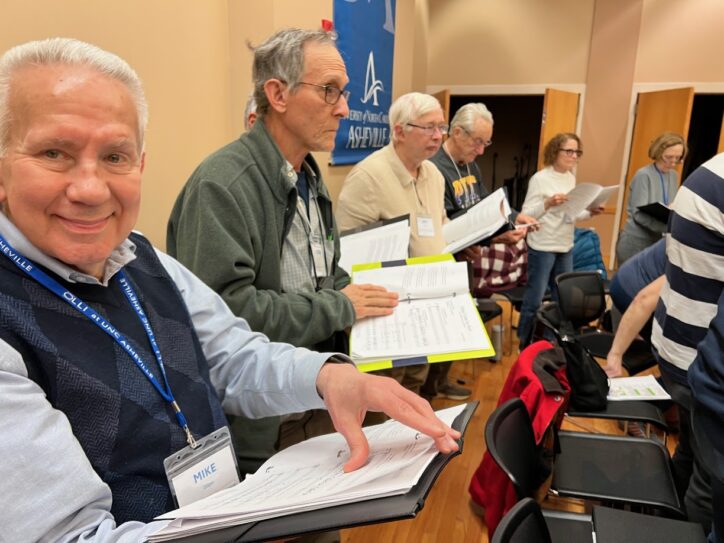 A member of the Asheville Senior Chorus smiles a the camera during a rehearsal.
