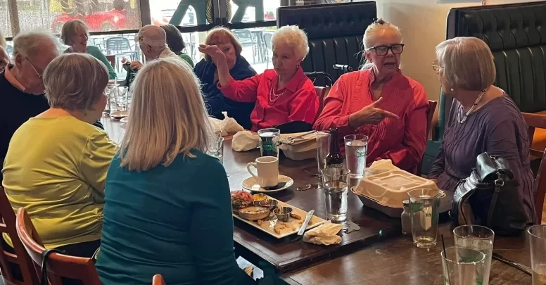 Asheville Senior Chorus members socializing and celebrating at a post-concert reception, building friendships and community connections through choral singing.