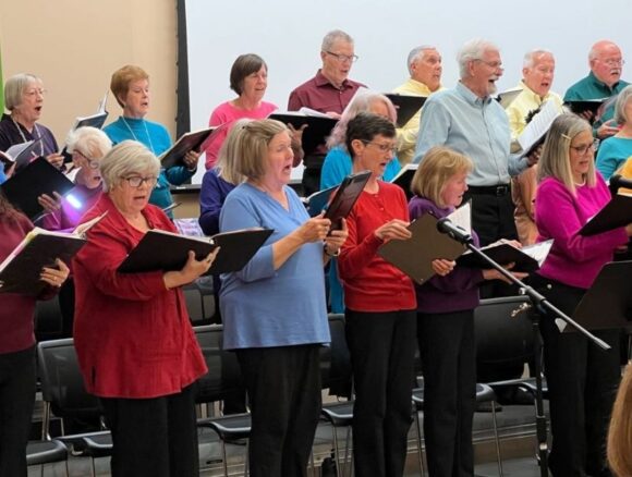 The Asheville Senior Chorus in colorful outfits during a concert performance